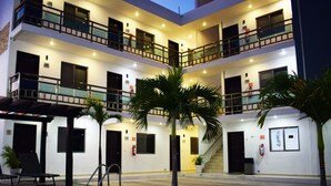 A multi-story hotel with balconies, a covered seating area, and a staircase leading to the upper floors. - Hotel Apartamentos Stone (Bacalar)