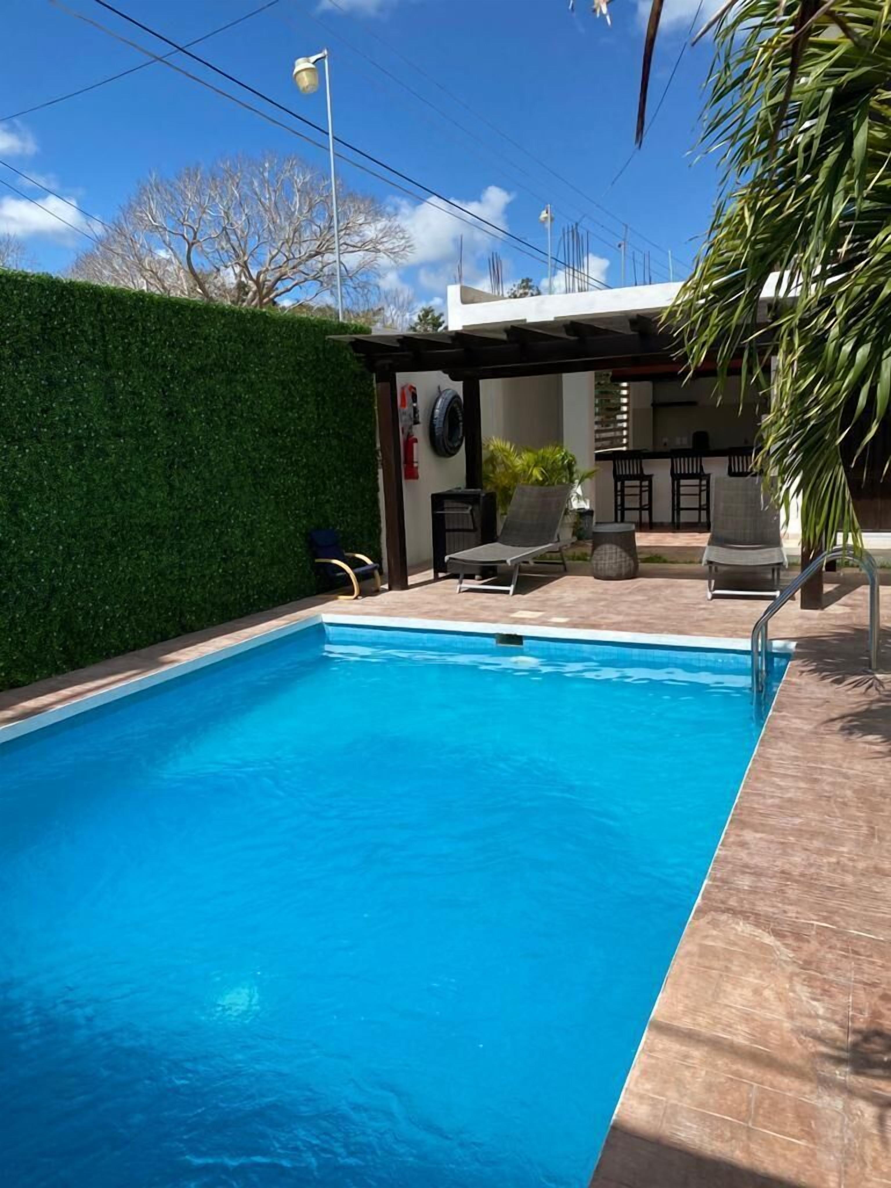 Une piscine agrémentée d’une pergola, de chaises longues et d’un espace bar.