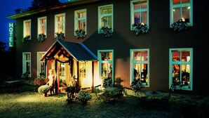 A hotel named "HAMMER" with a welcoming entrance, multiple windows with flower boxes, and a cobblestone ground. - Hammers Landhotel Gmbh (Teltow)