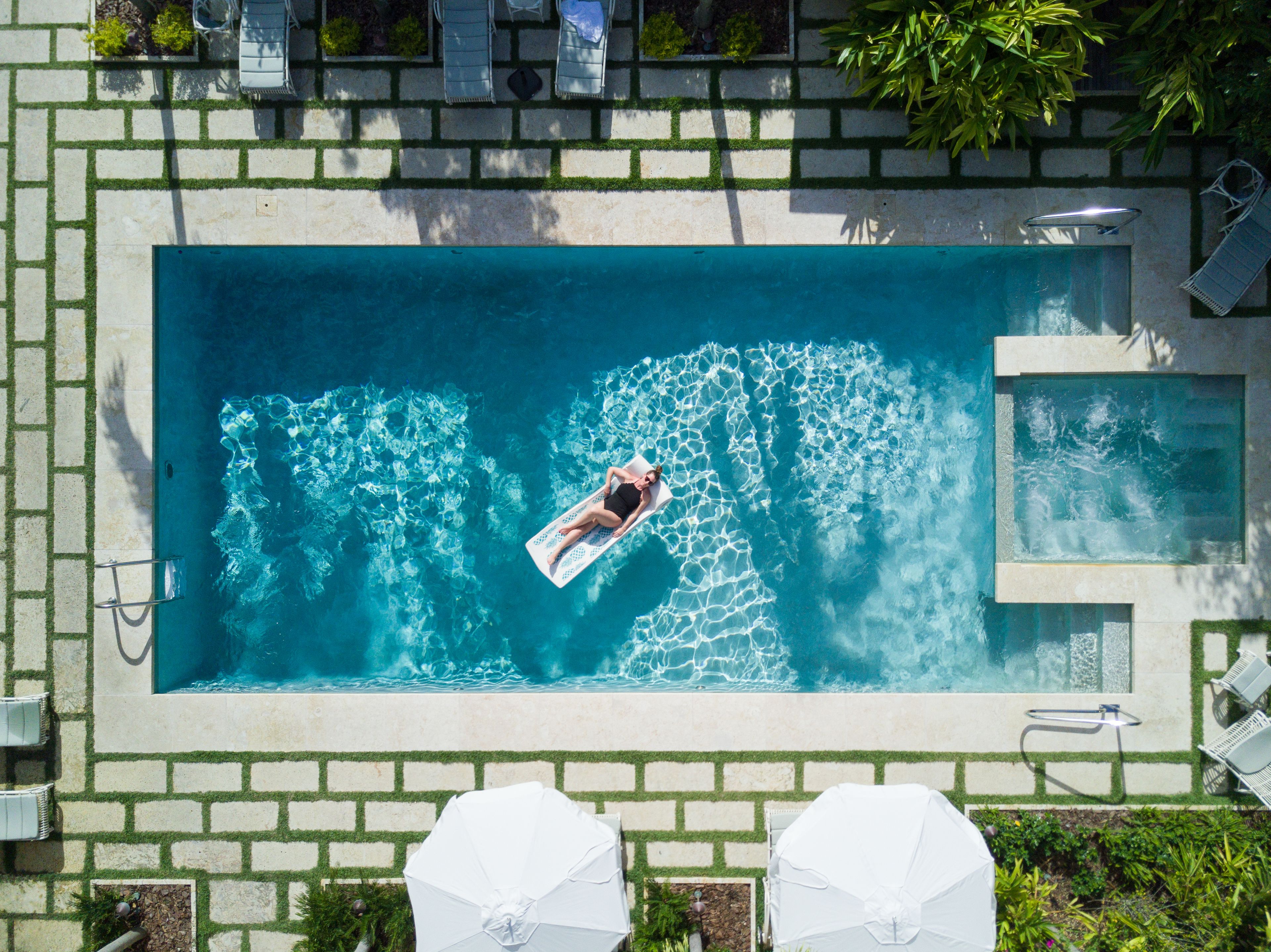 A rectangular swimming pool with a person lying on a floating mat.