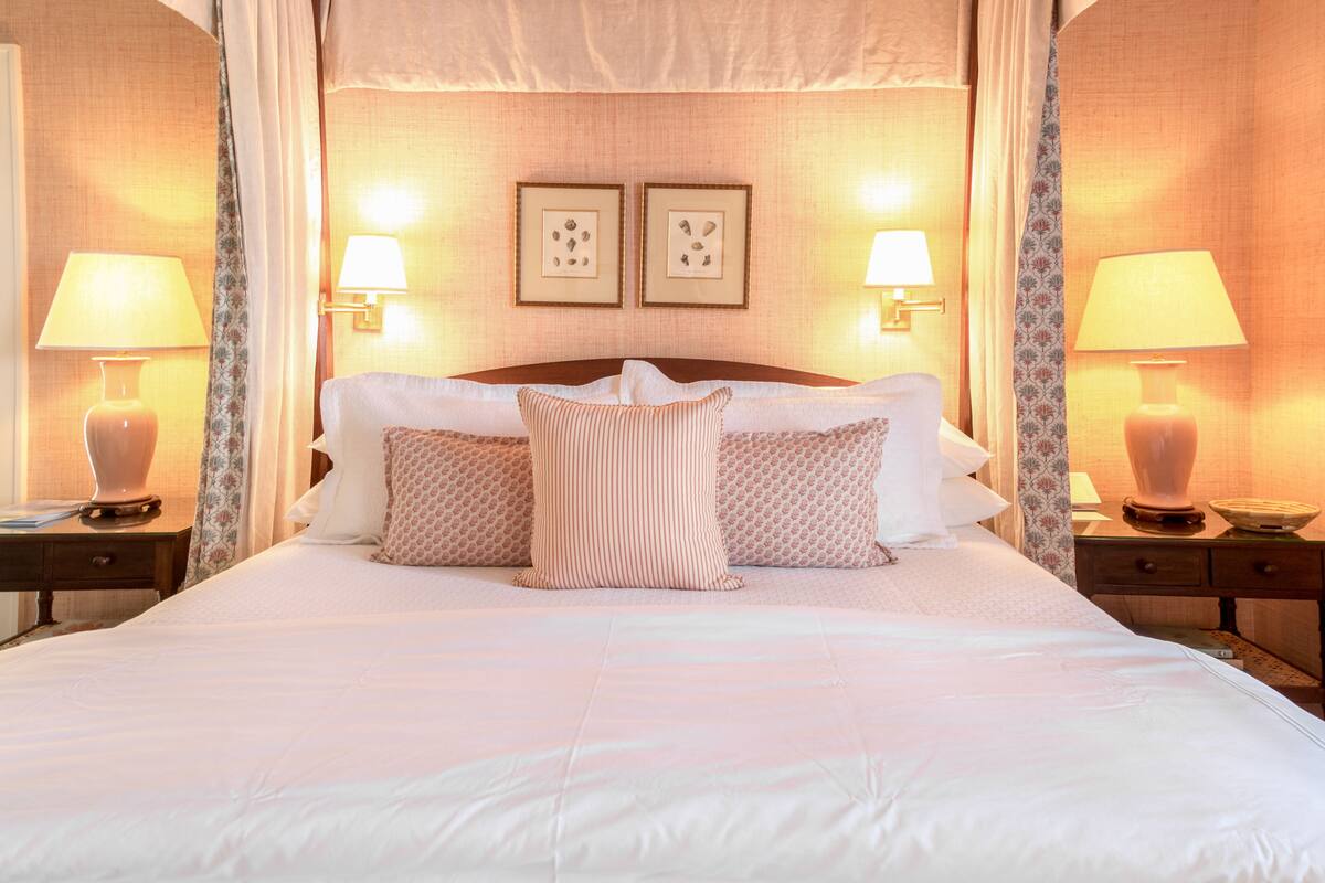 Habitación de hotel con una cama grande, dos mesitas de noche con lámparas y dos cuadros en la pared.