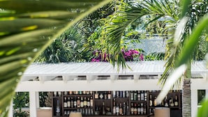 Et barområde med en hvid pergola, træstole og en bar fyldt med flasker.