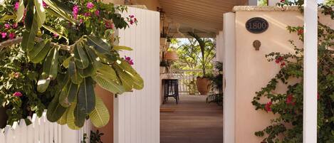 A covered entrance with a white pergola, a stone pathway, and a wall with a plaque.