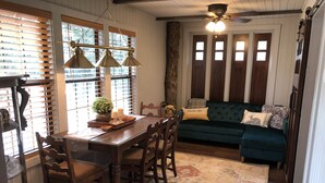 A dining area with a wooden table and chairs, a chandelier, and a patterned rug.