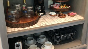A kitchenette with a coffee maker, jars, and a mirror.