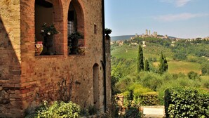 A rustic building with arched windows and a view of a hillside town.