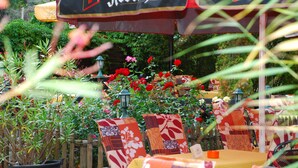 An outdoor seating area with tables and chairs, surrounded by potted plants and flowers. - Aragon am Lennepark (Ahrensfelde)