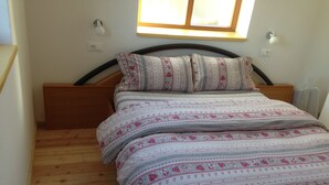 Ein Einzelbett mit Holz-Kopfteil, ein Fenster darüber und eine gesteppte Bettdecke.