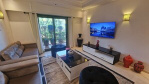 A modern living room with a sofa, ottoman, TV, and decorative vases. - Elegant Gueliz Retreat near Majorelle (Marrakech)
