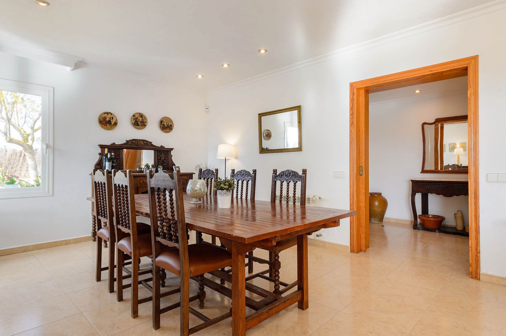 Une salle à manger avec une table et des chaises en bois, un miroir et des assiettes décoratives accrochées au mur.