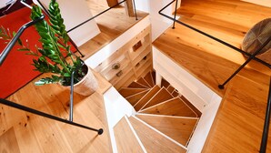 Eine Holztreppe mit weißer Geländer und einer Zimmerpflanze auf der linken Seite.
