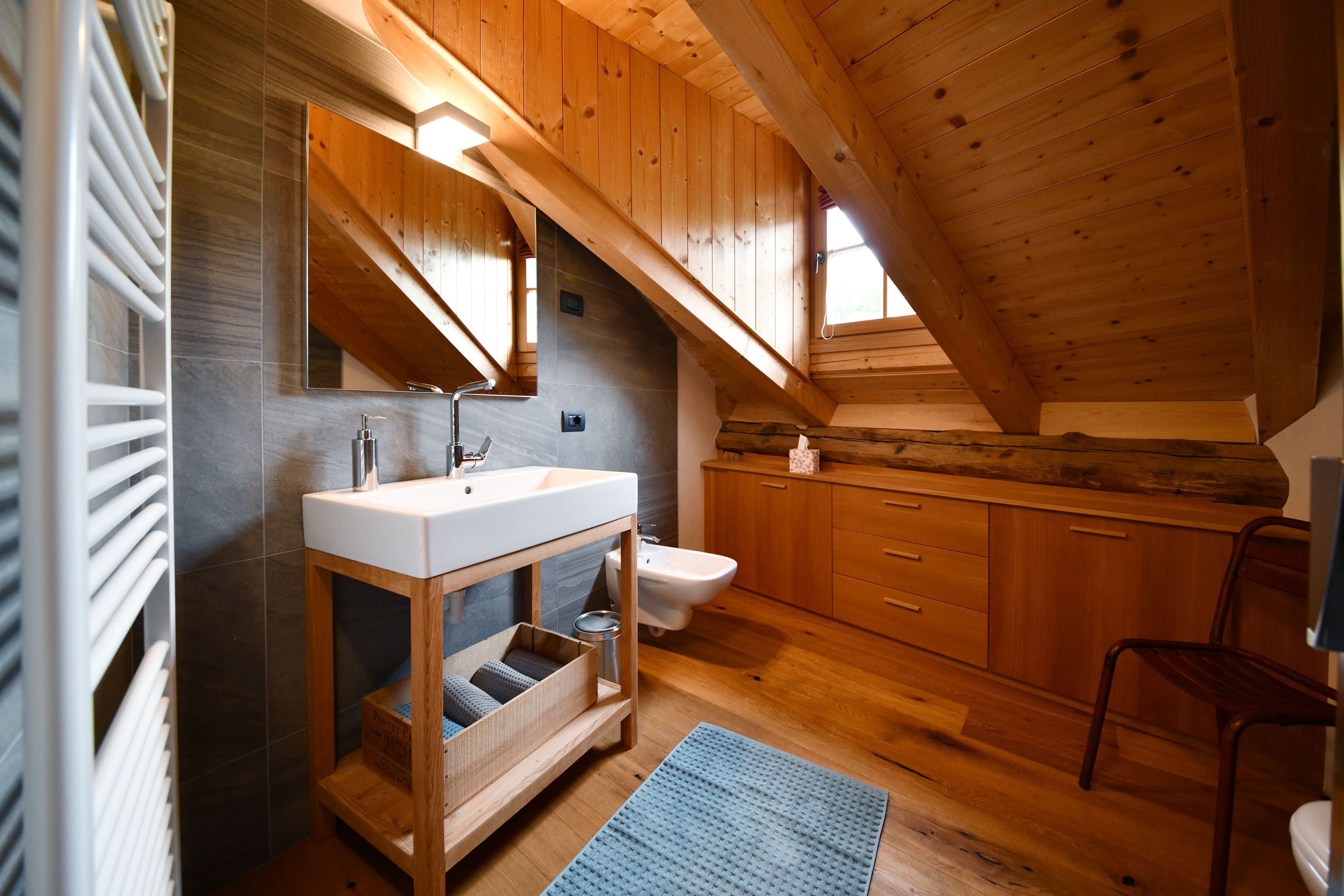 Un baño moderno con tocador de madera, un espejo grande, un bidé y techo de madera.