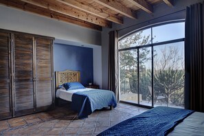 Ein Schlafzimmer mit einem Bett, einem Kleiderschrank und einem großen Fenster mit Blick auf Bäume.