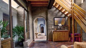 A spacious hallway with a wooden staircase, stone walls, and a view of a blue-lit room. - El Faro de Guanajuato (Guanajuato)