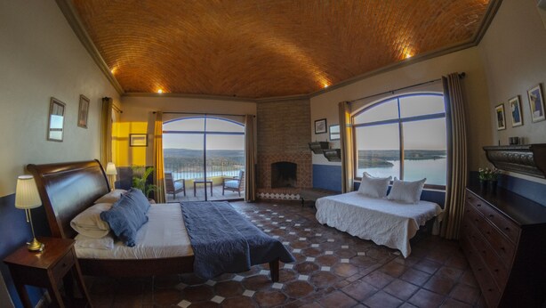 A bedroom with a large bed, a smaller bed, a fireplace, and a view of the water. - El Faro de Guanajuato (Guanajuato)