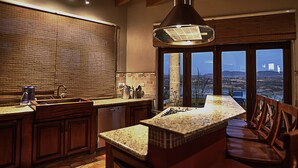 A kitchen with wooden cabinets, a granite countertop, a built-in stove, and a large window overlooking a landscape. - El Faro de Guanajuato (Guanajuato)