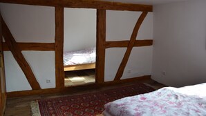 Een slaapkamer met een bed, een houten plafond en een kamerkleed met dessin.