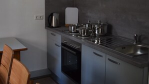 Een compacte keuken met roestvrijstalen apparatuur, een eettafel met stoelen en een klein aanrecht.