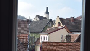 Een smalle straat met traditionele gebouwen, een kerktoren en een rode deur.
