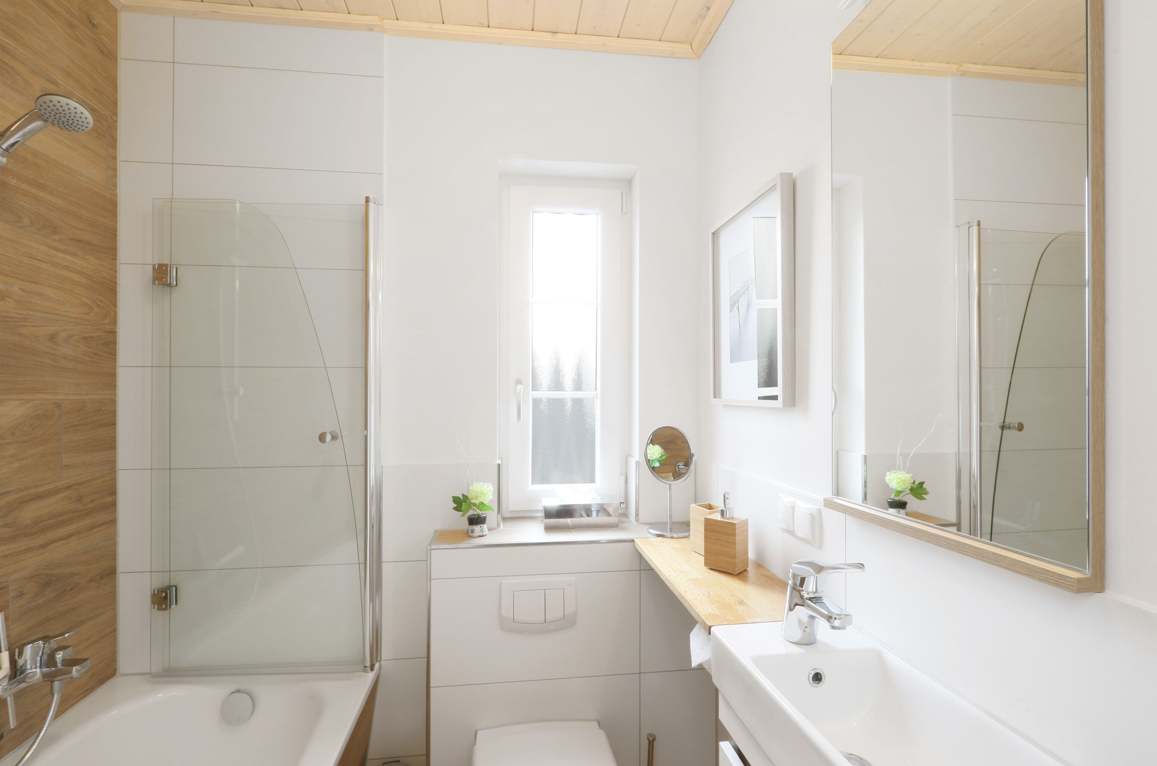 A modern bathroom with a glass shower, a window, a sink, and a mirror.