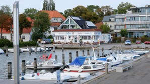 A marina with several boats docked, a restaurant with outdoor seating, and a building with a red roof.