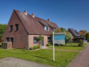 A brick house with a sloped roof, a small porch, and a signboard.