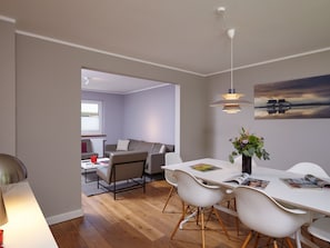 Un espacio moderno de estar con comedor, sofá y vistas al exterior.