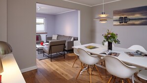 A modern living space with a dining area, a sofa, and a view of the outside. - 5 * Holiday home Düneneck 10 - Holiday home Düneneck 10 (Sankt Peter-Ording)