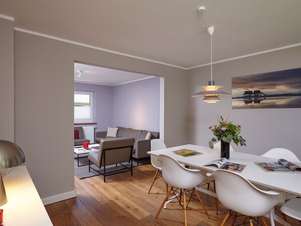 A modern living space with a dining area, a sofa, and a view of the outside.