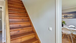 A wooden staircase leading to a room with a white wall and a painting of a bridge. - 5 * Holiday home Düneneck 10 - Holiday home Düneneck 10 (Sankt Peter-Ording)