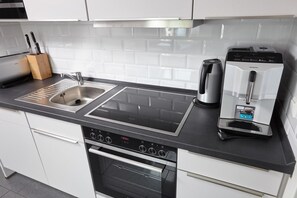Una cocina moderna con un lavamanos de acero inoxidable, una cafetera y un horno empotrado.