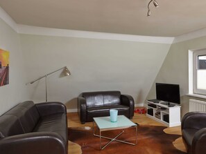 Una sala de estar con un sofá, una mesa de centro, un televisor y un radiador.
