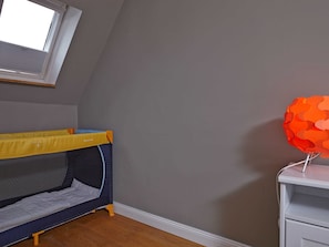 A child's bunk bed with a yellow top and a grey bottom, a white nightstand with a red spherical object on it, and a window with blinds. - Apartment for 4 persons Düneneck 6 - Apartment for 4 persons Düneck 6 (Sankt Peter-Ording)
