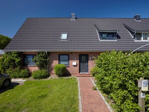 A two-story brick house with a dark tiled roof, a small window, and a door. - Apartment for 4 persons Düneneck 6 - Apartment for 4 persons Düneck 6 (Sankt Peter-Ording)