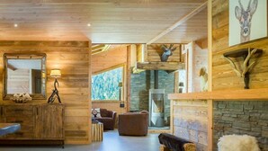 L’intérieur d’un chalet confortable, avec une cheminée, un mur en pierre et des meubles en bois.