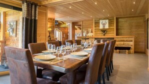 Un espace repas avec une longue table en bois dressée pour le repas, entourée de chaises en cuir.