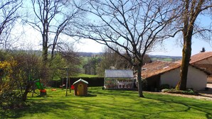 A rural setting with a green lawn, a small wooden structure, and a building with a tiled roof. - La Petite Fontaine, small cottage in a very quiet hamlet (ecuras)