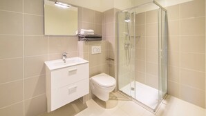 Un bagno moderno con box doccia in vetro, lavandino bianco e water.