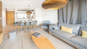 Un soggiorno moderno con un divano grigio, un'area pranzo con un tavolo imbandito per quattro persone e una cucina sullo sfondo.