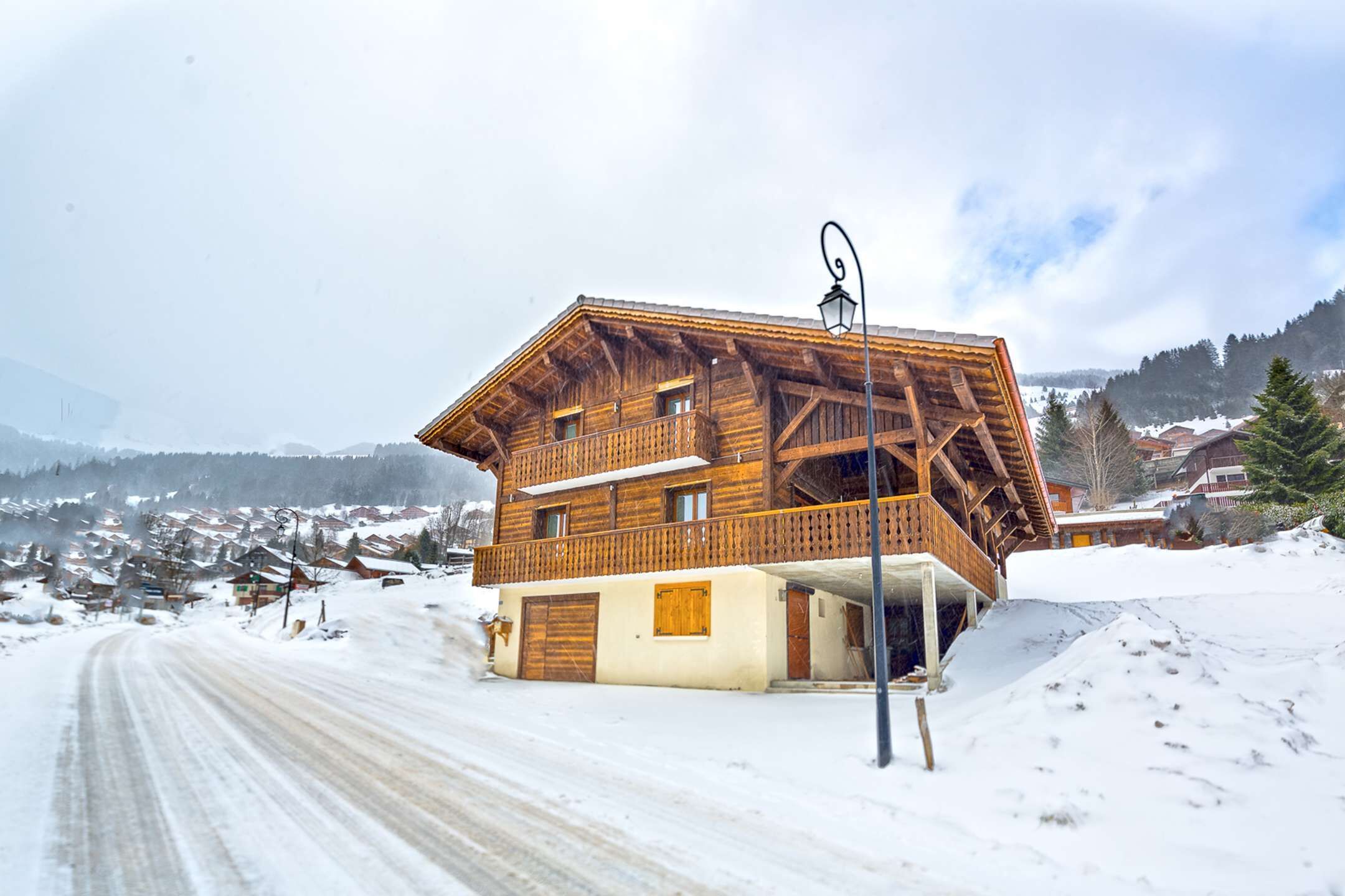 Eine Holzhütte mit Balkon, gelegen an einem verschneiten Hang unter blauem Himmel.