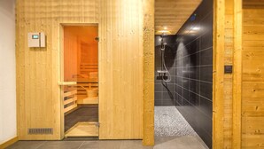 A wooden sauna room with a wooden door, a bench, and a towel rack. - Luxurious chalet - close to the centre, private sauna and spa, large open spaces (Châtel)