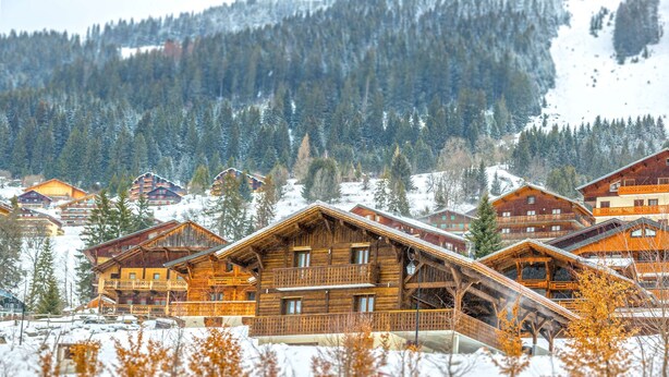 A cluster of wooden cabins with balconies, set against a snowy mountain backdrop. - Luxurious chalet - close to the centre, private sauna and spa, large open spaces (Châtel)