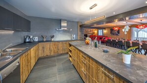 A modern kitchen with a central island, built-in appliances, and a dining area with red seating. - Luxurious chalet - close to the centre, private sauna and spa, large open spaces (Châtel)