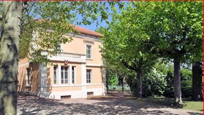 Un bâtiment à la façade beige, doté de grandes fenêtres et d’un toit rouge.