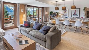 A modern living room with a sofa, coffee table, and dining area with chairs and a table. - Luxury flat 6 pers. - fireplace, close to the centre and slopes (CHATEL)