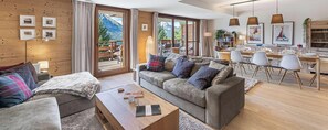 A modern living room with a sofa, coffee table, and dining area with chairs and a table. - Luxury flat 6 pers. - fireplace, close to the centre and slopes (CHATEL)