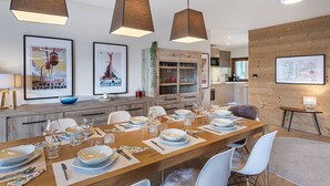 A modern dining area with a long wooden table set for a meal, pendant lights, and framed artwork on the walls. - Luxury flat 6 pers. - fireplace, close to the centre and slopes (CHATEL)