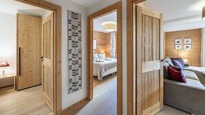 A modern hotel room with wooden walls and floors, a bed with a floral bedspread, and a bedside table with a lamp. - Luxury flat 6 pers. - fireplace, close to the centre and slopes (CHATEL)