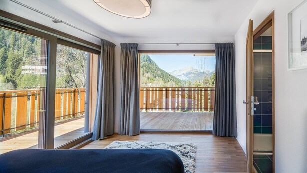 A bedroom with a large sliding glass door leading to a balcony with a wooden railing, offering a view of a mountainous landscape. - Luxury flat for 8 people - modern, close to the centre and slopes (CHATEL)