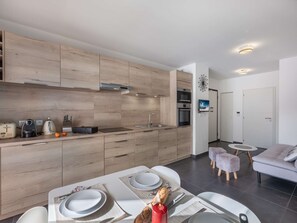 Eine moderne Küche mit Holzausstattung, einem eingebauten Backofen und einem Essbereich mit Tisch für zwei Personen.
